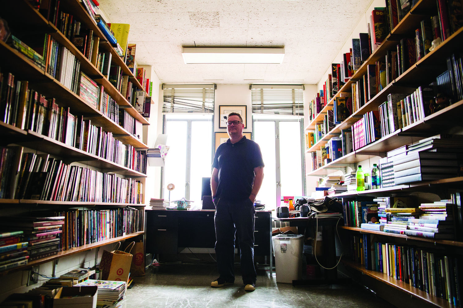 Roy T. Cook standing in his office surrounded by shelves of books.
