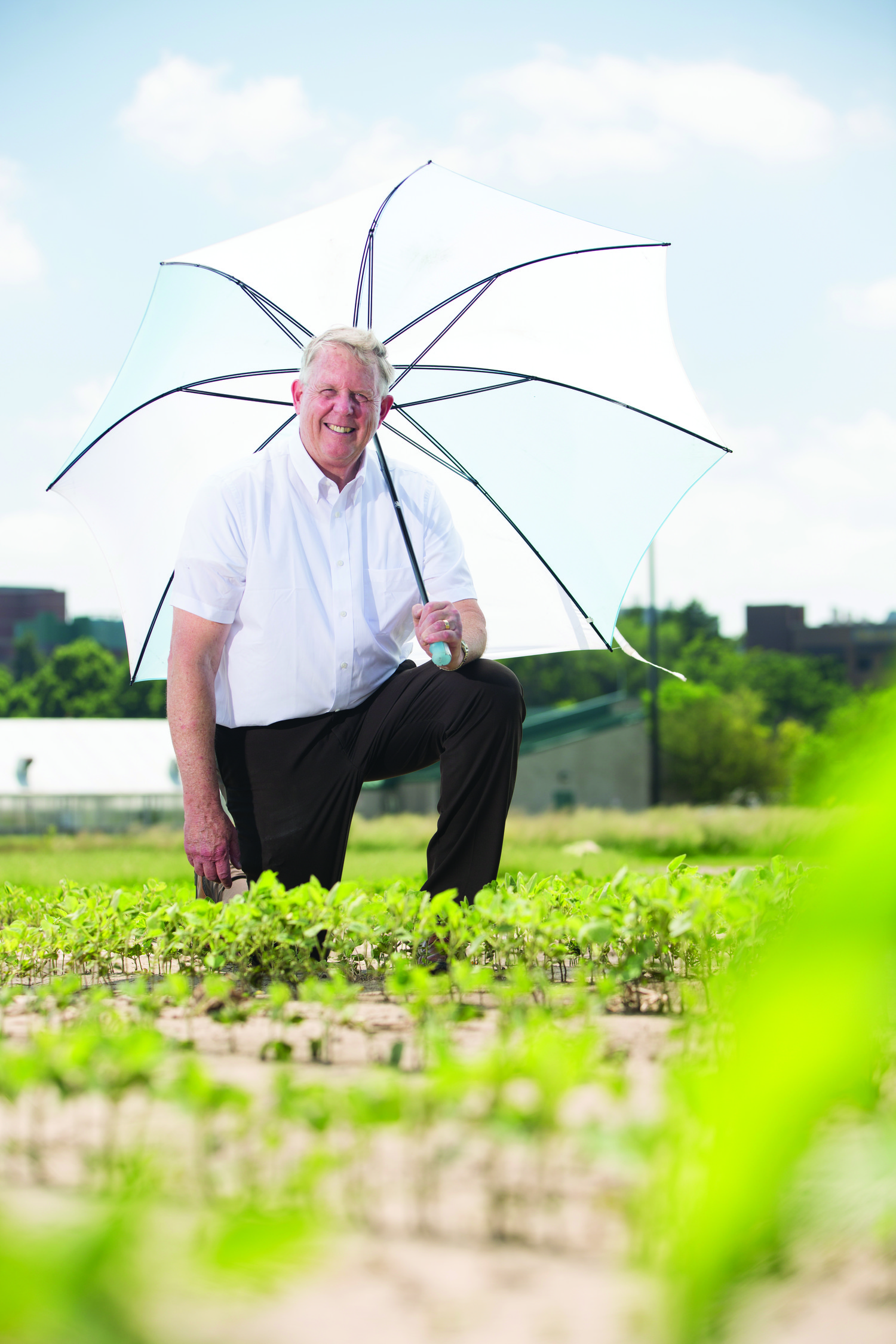 Mark Seeley standing in a garden holding a white umbrella